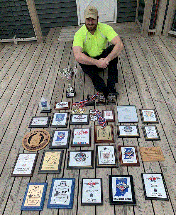 Joey Zadik displays his many trophies and plaques from IDPA and USPSA Compeitions.